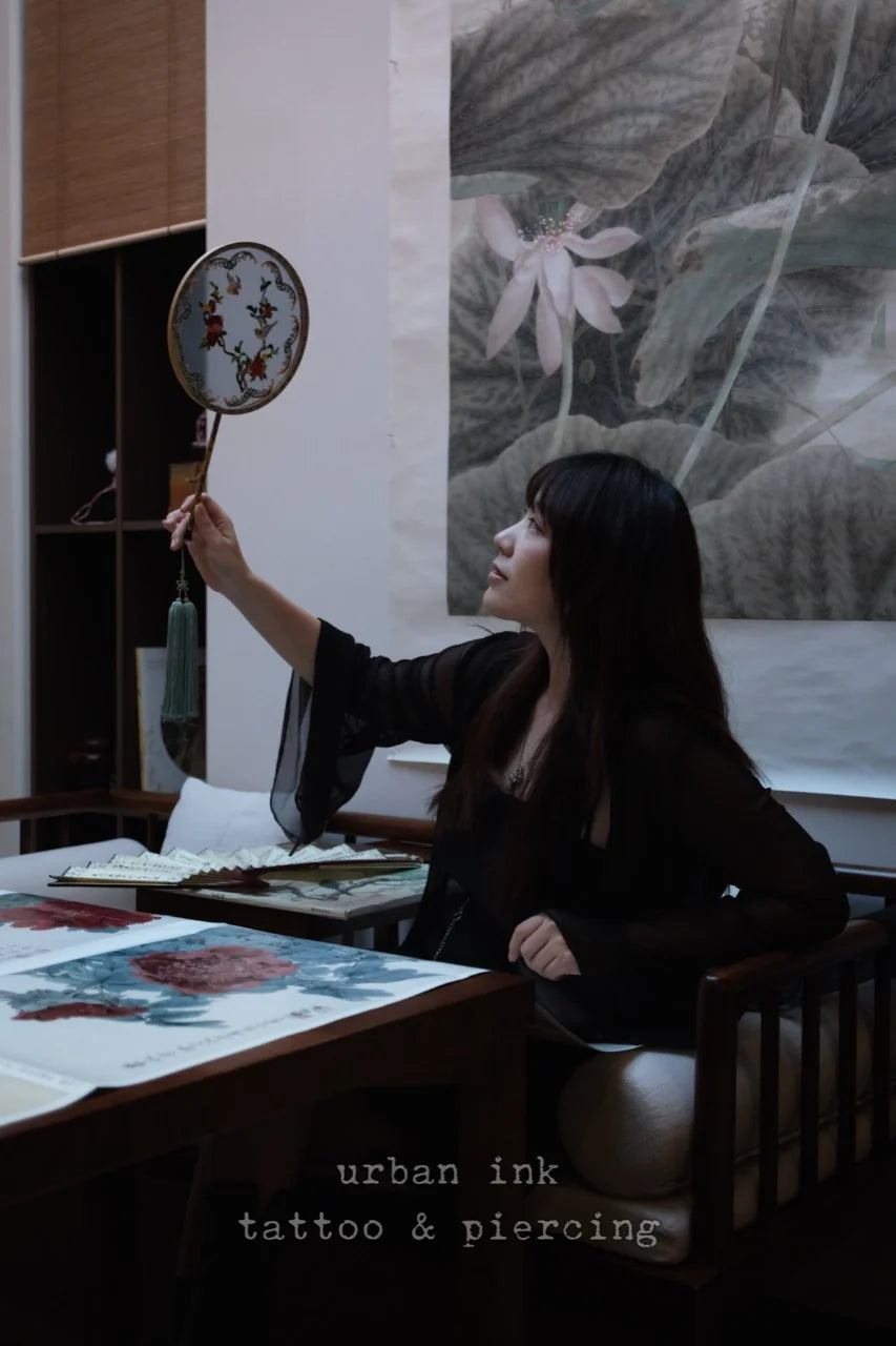 An artist working with an embroidered fan inside Urban Ink