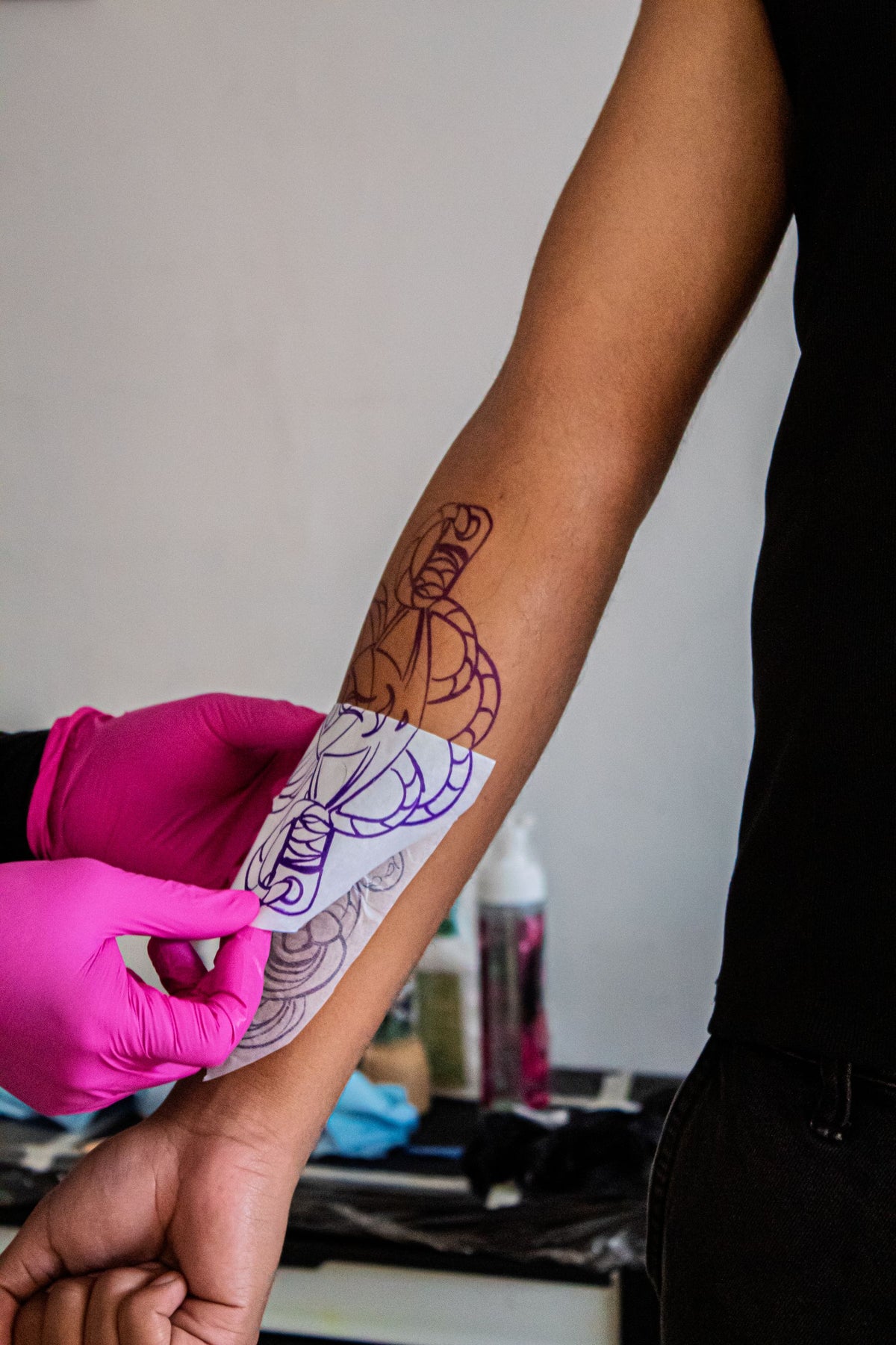 Tattoo artist applying a stencil while planning placement on a client arm