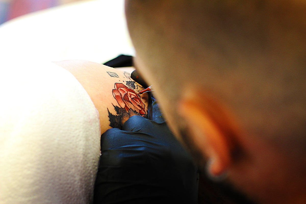 Tattoo artist creating a floral tattoo that shows cover-up design planning