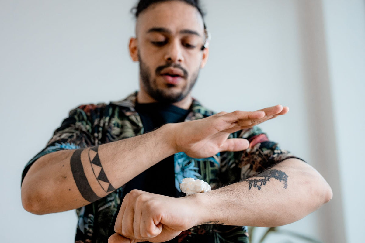 Person applying cream to a tattooed forearm for itchy tattoo aftercare