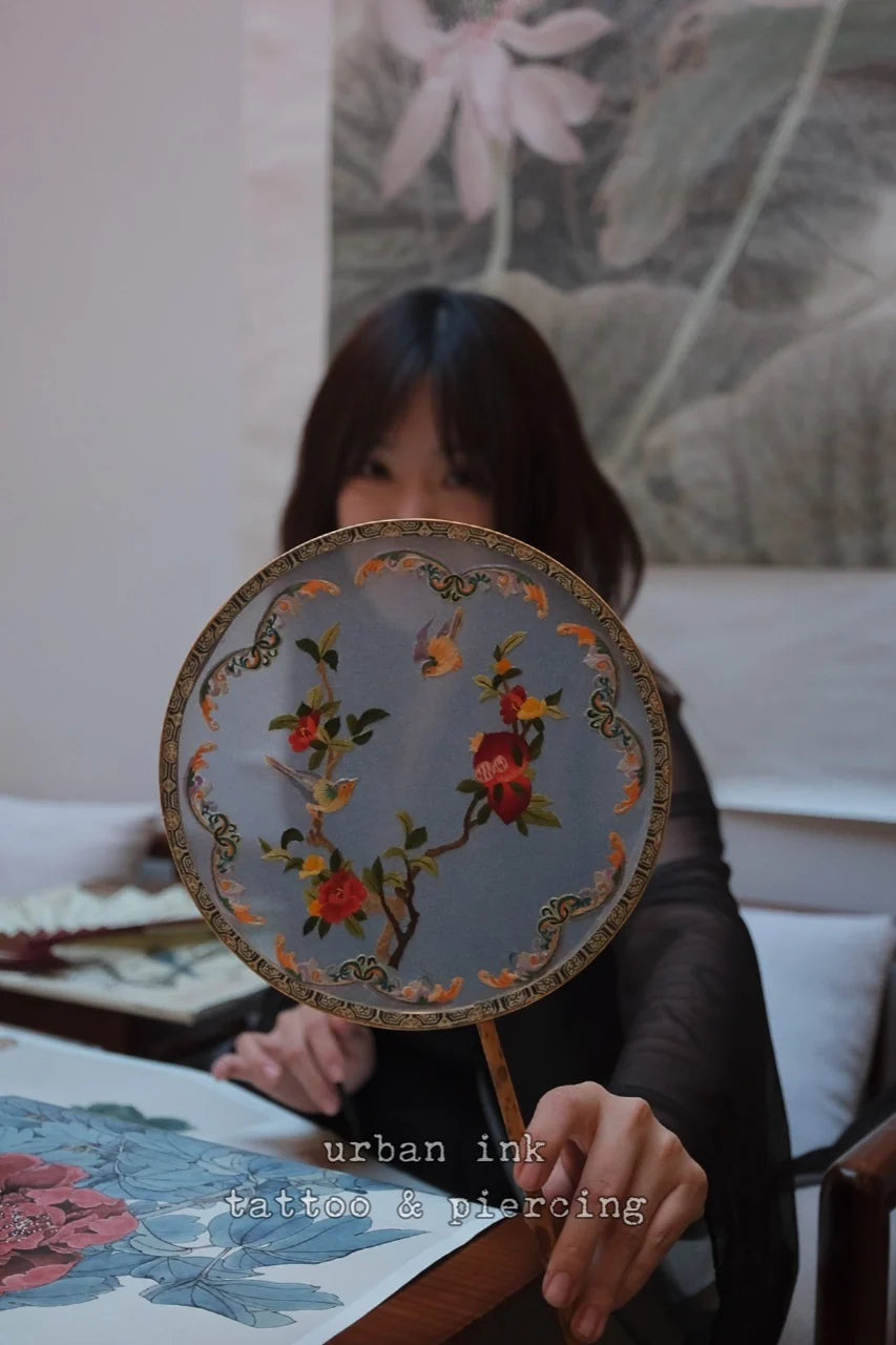 A client holding an embroidered fan inside Urban Ink